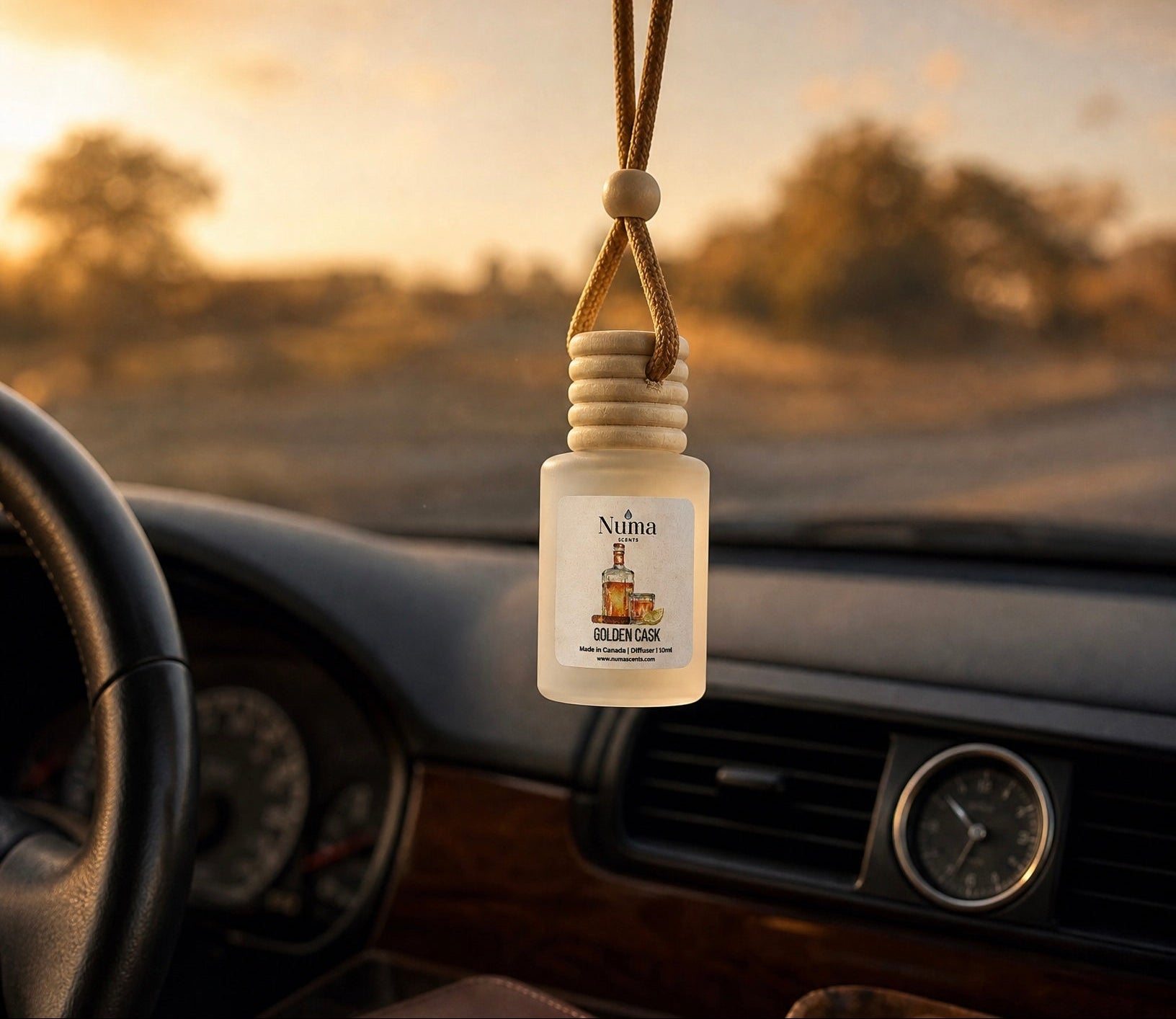 Car air freshener hanging from a car's rearview mirror with a scenic road in the background
